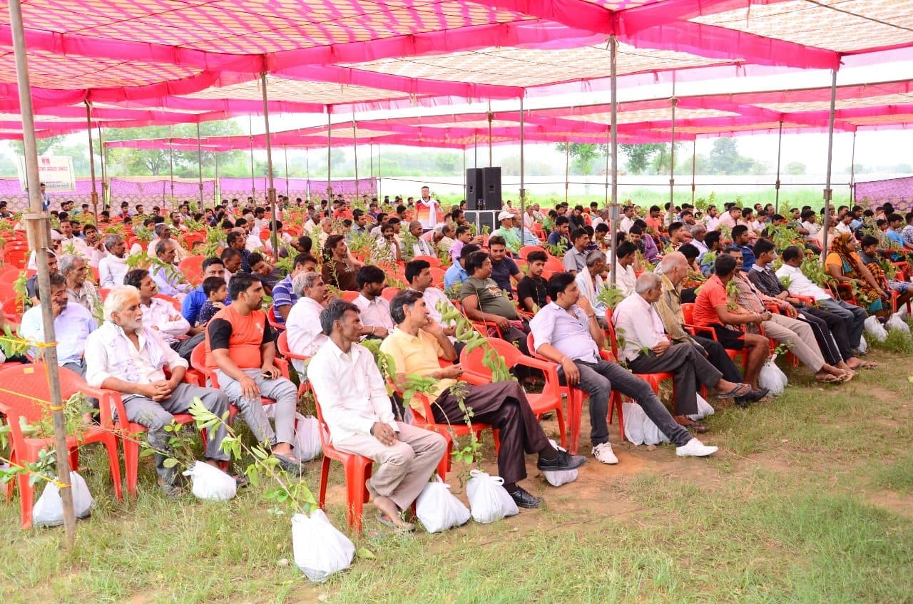 Farmers seated under the tent with their sapling packets at a 2018 camp